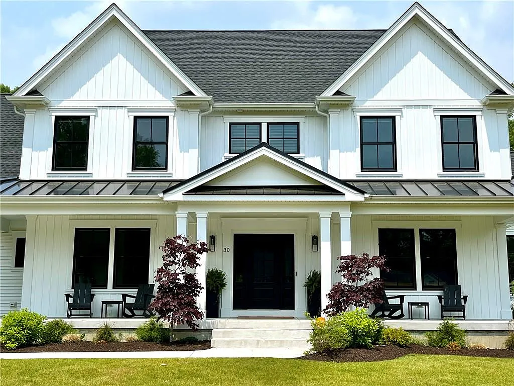 White shingle-style house with covered front porch and dark windows